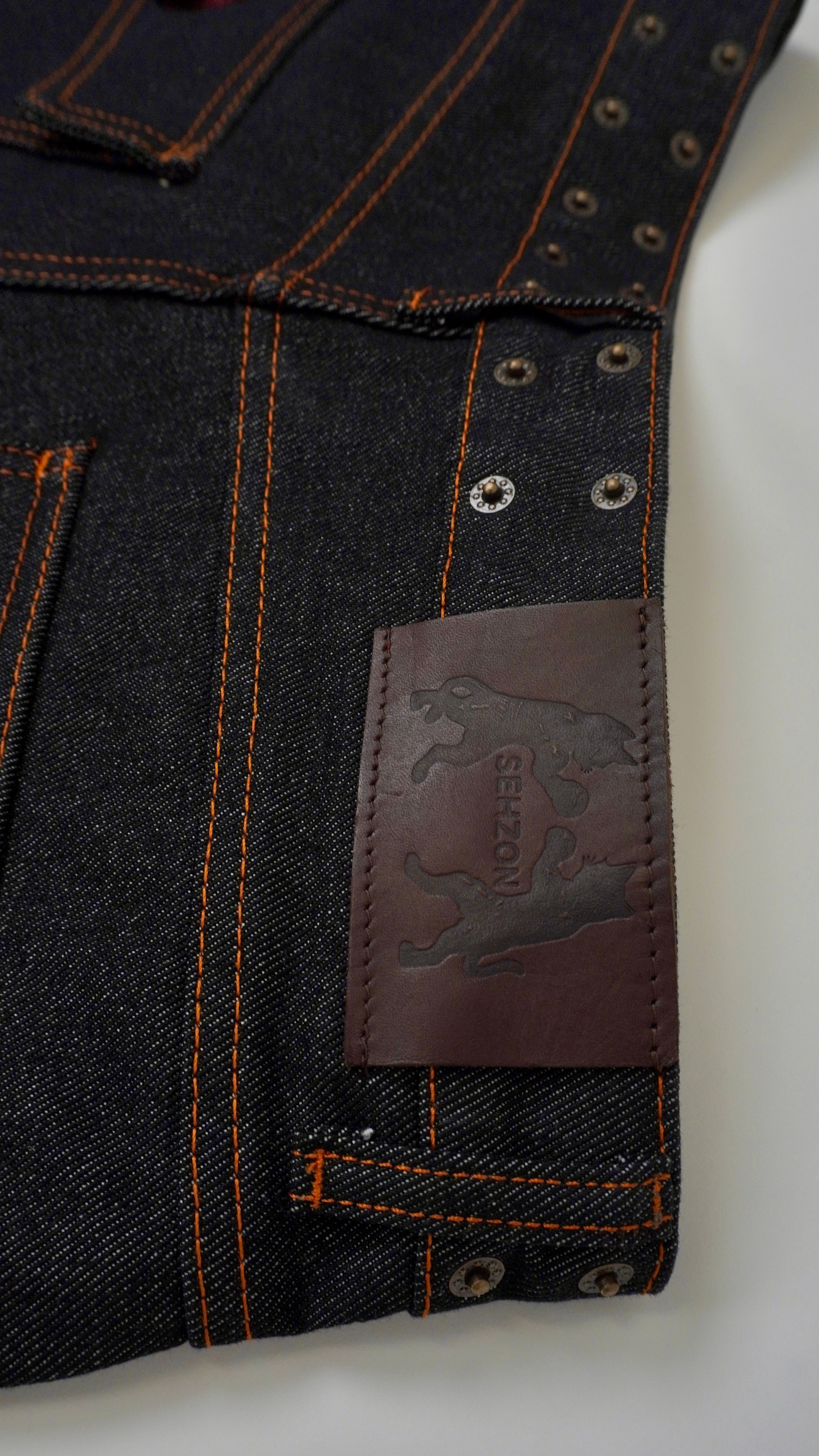 Close-up of dark denim jeans with a brand label on a light gray background