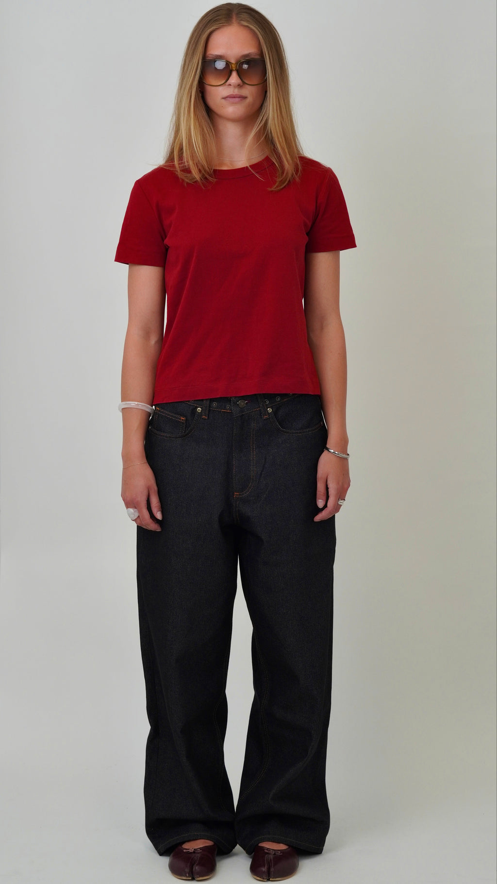 Person wearing a red t-shirt and black pants on a white background