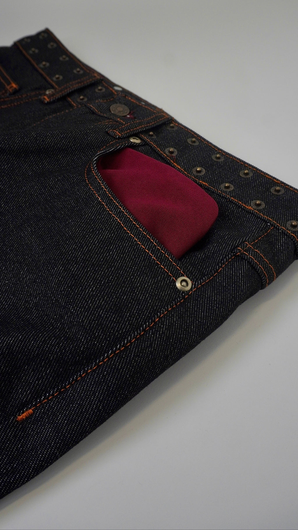 Dark blue jeans with a red pocket on a white background